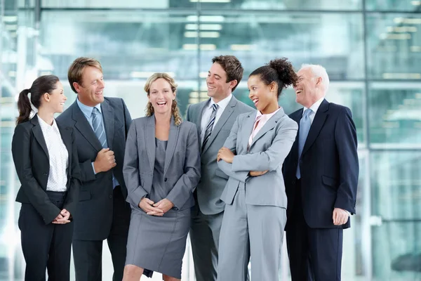 她绝对是当月的雇员 一群快乐的商人站在一起 微笑着围绕着一个同事的肖像 — 图库照片