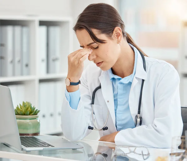 Stress, depression and tired female doctor suffering from a headache or mental health while sitting in an office with laptop. Frustrated, upset and overworked healthcare or medical worker in hospital.
