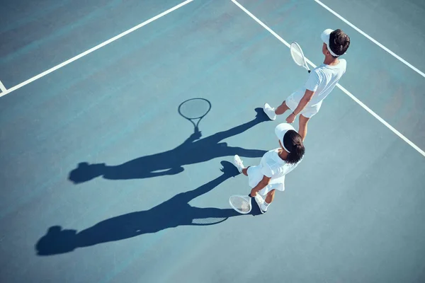 Sport, fitness and tennis player team discussion of game strategy while walking together on a tennis court from above. Professional, athletic and competitive man and woman planning and training.