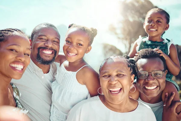 Portrait, happy black big family and love as they smile on vacation, trip or holiday. Ancestry, African people or grandparent, fathers and mother with kids together in the shining sun or sunshine
