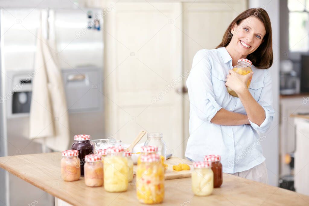 Shes proud of her domestic skills. A mature woman holding a jar to her chest in the kitchen