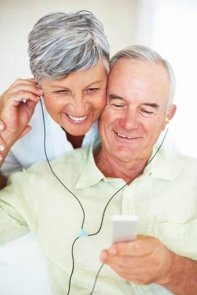 Mature couple listening music at home. Handsome mature man and woman listening music at home