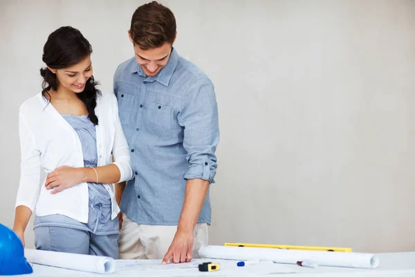 Happy couple going through house plan. Portrait of happy young couple smiling while going through house plan