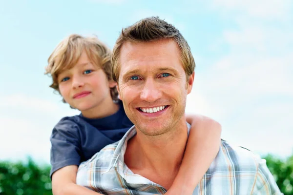 笑成熟的男人骑着他的儿子在天空中 一个面带微笑的成熟男人骑着他的儿子在天空中滑行的画像 — 图库照片