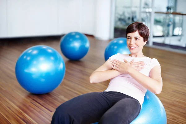 Woman doing sit ups on exercise ball. Healthy woman doing abdominal sit ups on exercise ball