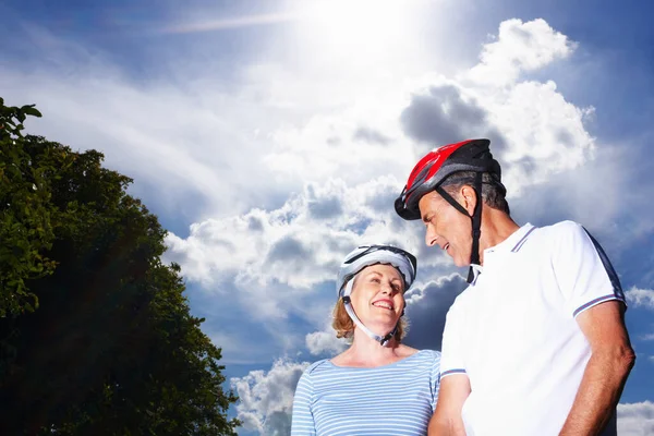 Loving couple wearing protective helmet against cloudy sky. Portrait of a loving couple wearing protective helmet against cloudy sky