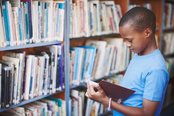 图书馆是富有创造力的人的好地方 一个非洲裔美国男孩在图书馆里欣赏一本好书 — 图库照片