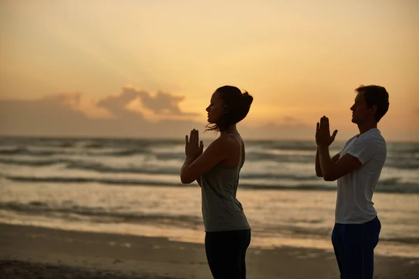 通过瑜伽实现健康和幸福 日落时一对夫妇在海滩上做瑜伽 — 图库照片