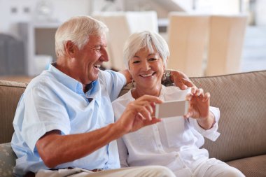Gerçek aşka peynir de. Kanepede otururken cep telefonlarıyla selfie çeken yaşlı bir çift.