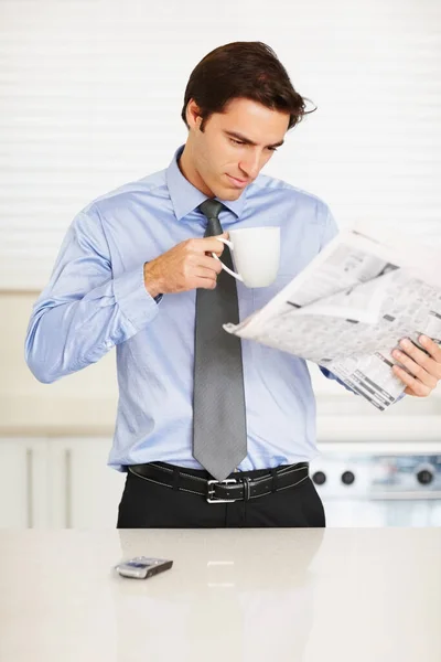 Young man drinking coffee while reading a financial newspaper. Young business man drinking coffee while reading a financial newspaper