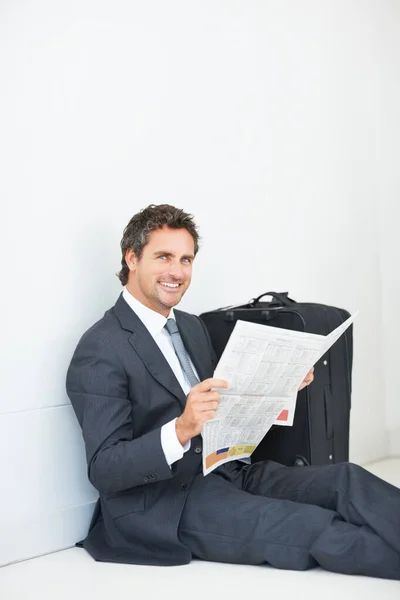 商人笑着看报纸 聪明的 面带微笑的商人坐在墙边看报纸 给你一个温暖的微笑 — 图库照片