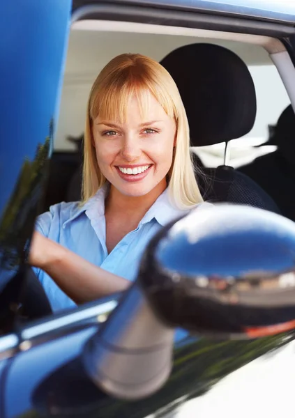 Pretty female smiling from the front seat of a car. Portrait of a smiling young woman sitting in the front seat of a car