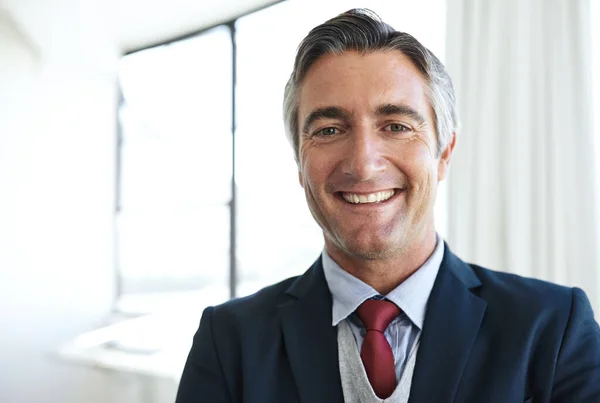 Hes a distinguished businessman in the financial field. Portrait of a smiling mature businessman in his office