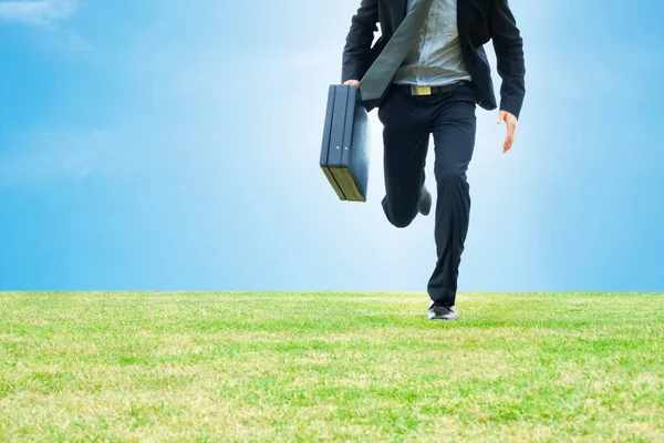 Business man running with a briefcase on a field. Cropped image of a business man running with a briefcase on a field - Copyspace