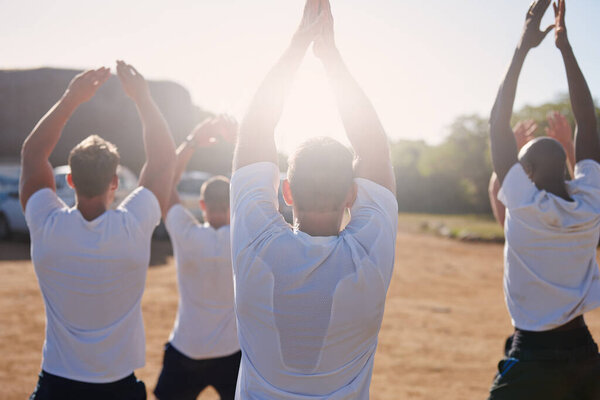 Getting fit with the help of bootcamp. Rearview shot of a group of men doing exercises at a military bootcamp