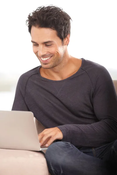 无线网络 一个英俊的年轻人在家里的笔记本电脑上上网 — 图库照片