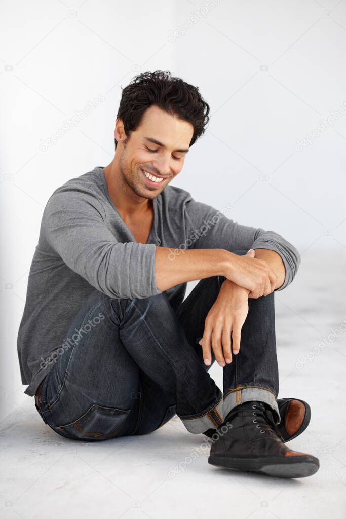 Hes got a carefree attitude. A handsome young man sitting crossed-legged and smiling with his eyes closed