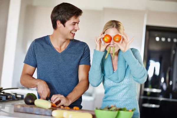 食べ物を楽しむときは 人生を楽しむのです 夫が食事の準備をしている間に野菜で面白い顔をする遊び心のある若い女性 — ストック写真