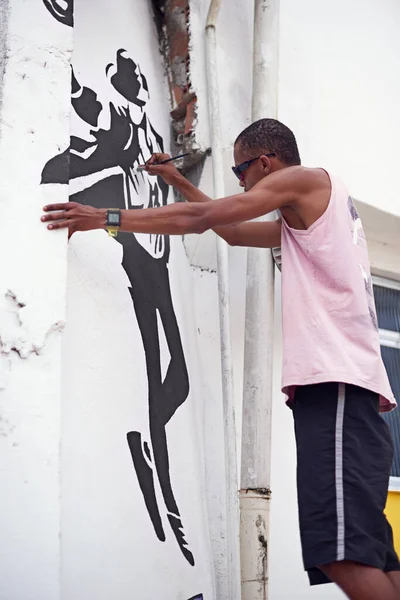 Expressing himself through art. a young graffiti artist painting a design on a wall
