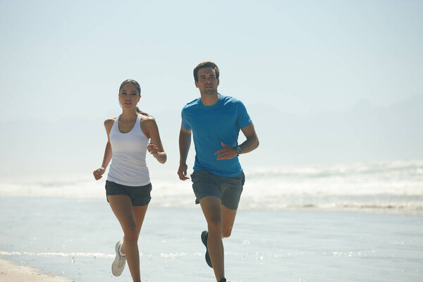 Theyre in it for the long run. a young couple jogging together on the beach