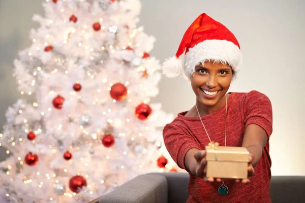 寛大なクリスマスの精神 カメラにクリスマスの贈り物の一つを示す美しい若い女性 — ストック写真