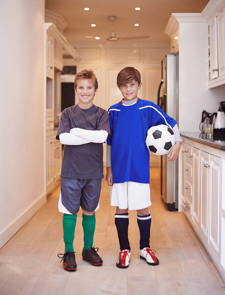 Boys will be boys. Portrait of two young boys in sports clothing standing indoors with a soccer ball