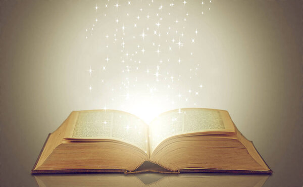 Be drawn into new worlds. an open storybook with light emanating from it