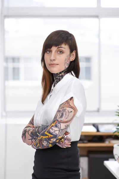 Shes ready to rock the corporate scene. A tattoo-covered young businesswoman in her office