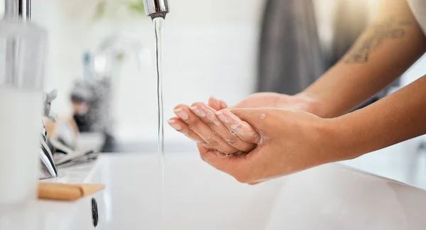 Water, soap and clean woman hands in bathroom for covid 19, corona virus or healthcare safety. Cleaning and wellness background with a person washing bacteria in foam liquid for skincare or hygiene.