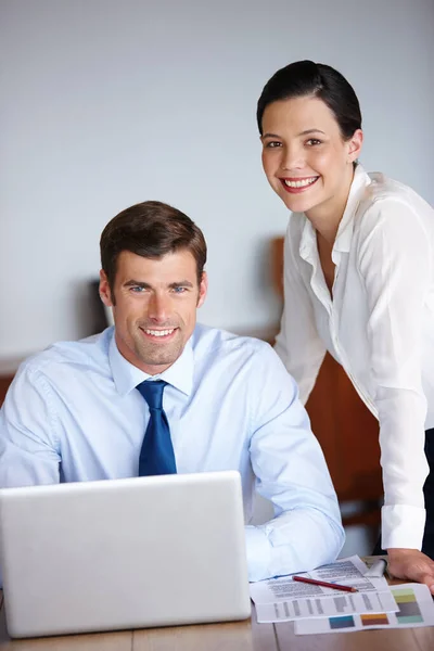 Ready to wrap up. Portrait of two business colleagues using a laptop in their office