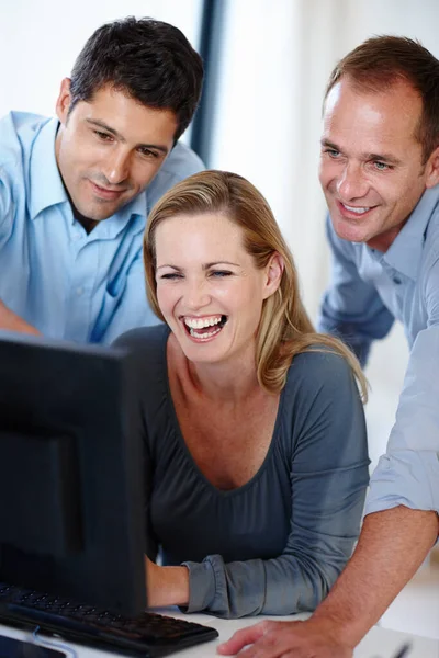 在这个办公室里 笑是唯一的良药 三位快乐的同事一边看电脑屏幕一边笑 — 图库照片