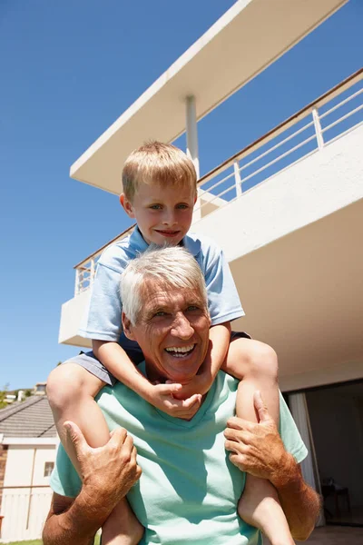 Im still fit enough to give piggyback rides. a grandfather giving his grandson a piggyback ride outdoors