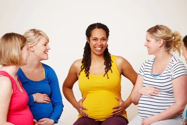 分享他们的经验 一群多种族的孕妇坐在一起进行友好的讨论 其中一个人在镜头前微笑 — 图库照片