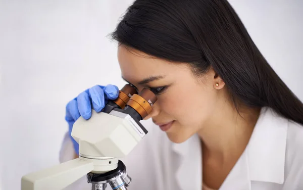 Hard at work improving quality of living. Portrait of a female scientist using a microscope