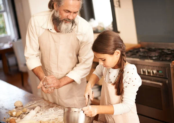 おじいちゃんは彼女に一つか二つ教えている 台所で焼く祖父と結びついている女の子が — ストック写真