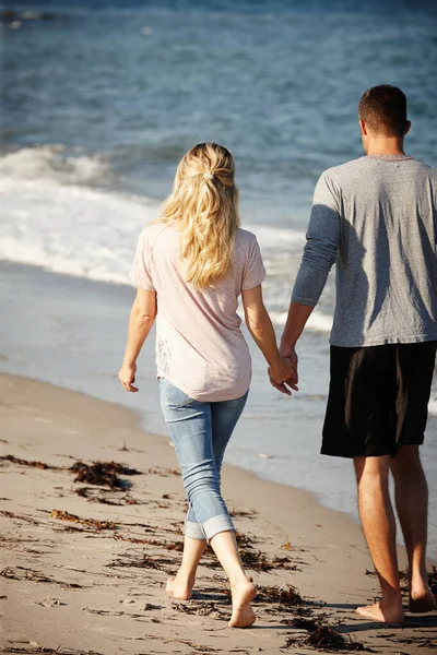 すべてから離れていく 砂浜に沿って手をつないで歩く若いカップルのレビューショット — ストック写真