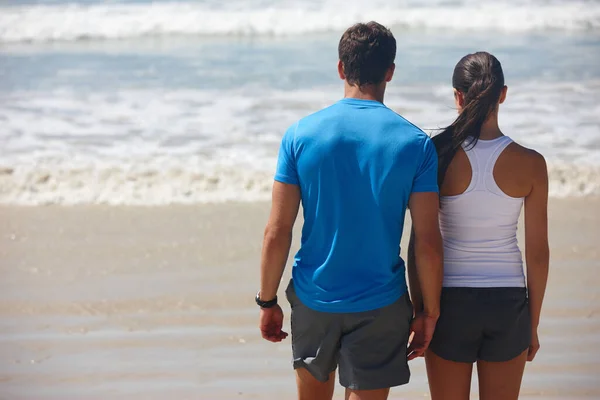 これは美しいです しかし それは彼女に比べて何も スポーツウェアを着てビーチを歩いている若いカップルのレビューショット — ストック写真