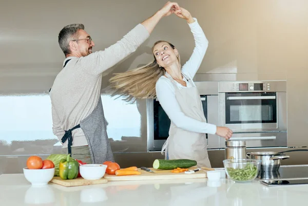 Dancing couple, cooking and love in the kitchen while preparing vegetables for a healthy, organic and vegan meal or salad. Happy man and woman with energy, joy and good health having fun at home.