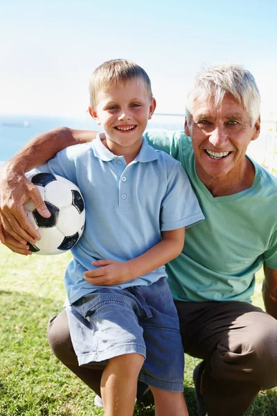 和爷爷踢足球 一个小男孩抱着足球 跪在祖父的膝上 — 图库照片