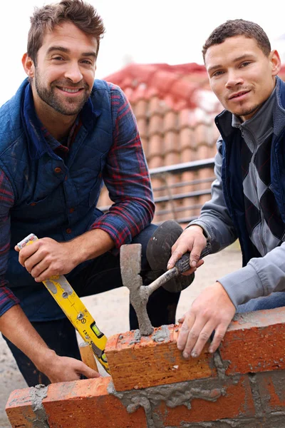 This wall will be strong. Portrait of a bricklayer and his apprentice at work