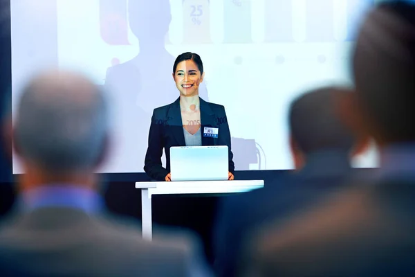 She has everyones attention. A beautiful young businesswoman giving a presentation at a press conference