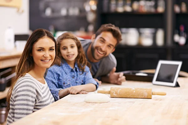 Theyre a family of foodies. Portrait of a happy family of three baking together in the kitchen with a digital tablet to aid them