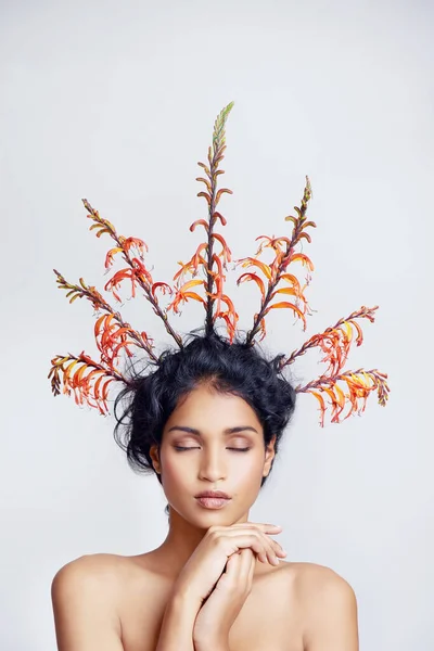 We are all of the natural world. Studio shot of a beautiful young woman with colorful branches in her hair