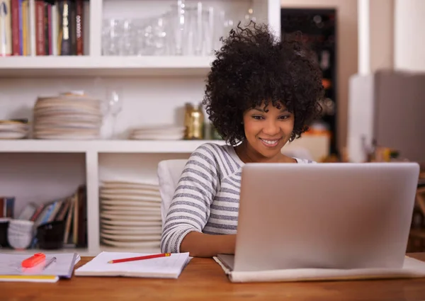 Getting a digital helping hand with her work. a young woman working on her laptop at home