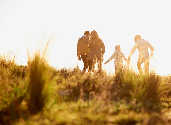 あなたが望む瞬間は永遠に続くでしょう 日没時に一緒に歩いている若い家族の完全な長さのショット — ストック写真