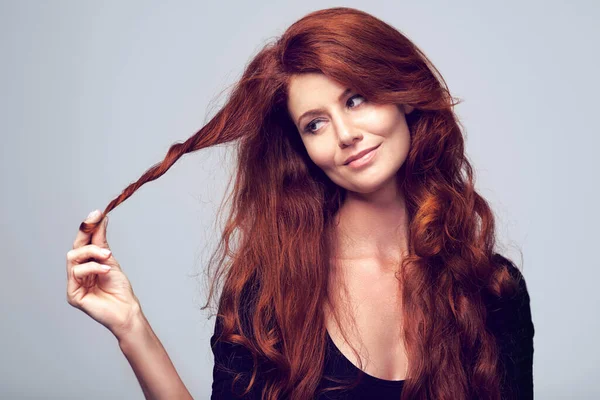 Time for a change. Studio shot of a young woman with beautiful red hair posing against a gray background