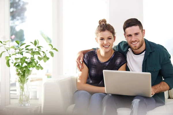 Connected to each other. Portrait of a happy young couple using a laptop while relaxing at home together