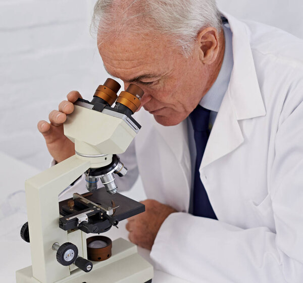 He has a keen eye for science. a mature scientist using a microscope