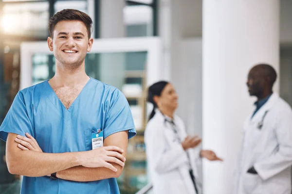 Portrait of a male nurse with his team in the background in the hospital. Happy, smiling and confident nurse with doctors in medicine, health and medical care. Medical team, healthcare and nursing.