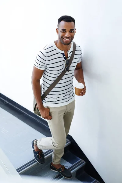会議に向かってる 彼の携帯電話とコーヒーを保持しながら 階段を歩くスタイリッシュな 気軽に疲れ若いビジネスマン — ストック写真